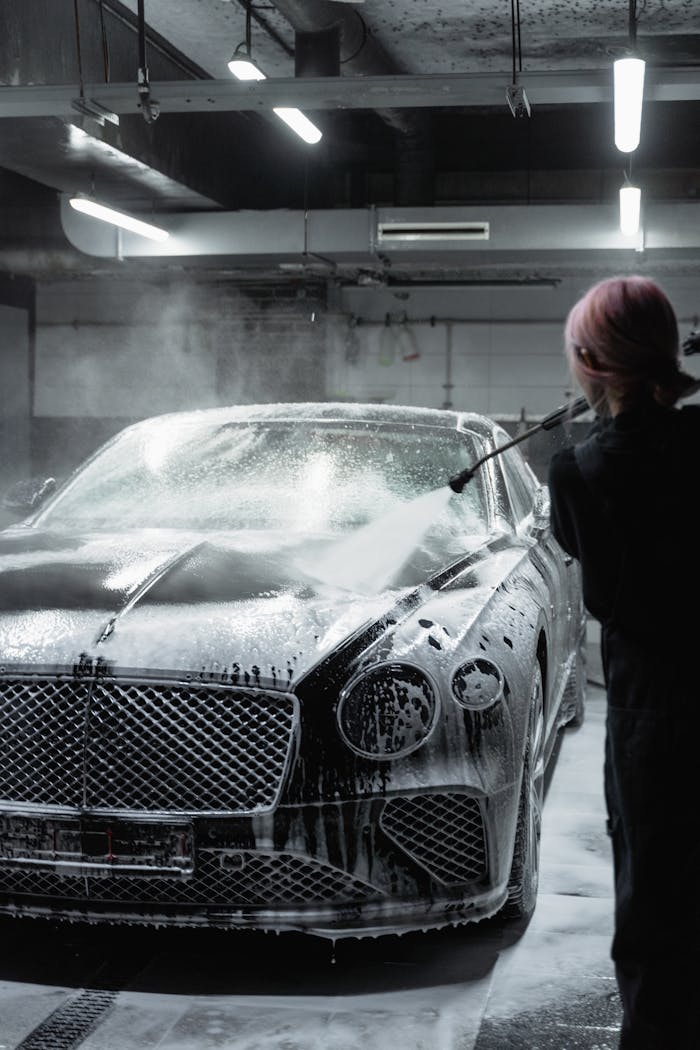 Crafting Captivating Headlines: Your awesome post title goes here A sleek black luxury car getting washed with foam by a worker in an indoor garage.
